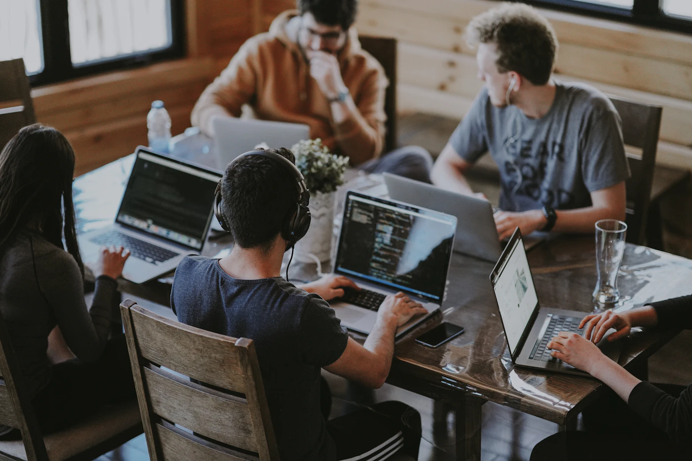 Personas colaborando con computadoras alrededor de una mesa de trabajo